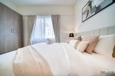 a bedroom with a large white bed with a window at Stylish Studio Apartment at Casa Grande, JVC by Deluxe Holiday Homes in Dubai