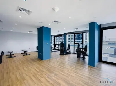a gym with treadmills and chairs in a building at Pleasant Studio Apartment at Azizi Riviera 13, Al Merkadh by Deluxe Holiday Homes in Dubai