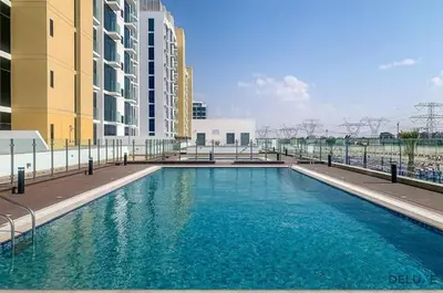 a large swimming pool in front of some buildings at Pleasant Studio Apartment at Azizi Riviera 13, Al Merkadh by Deluxe Holiday Homes in Dubai