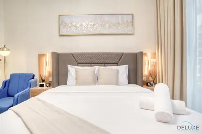 a bedroom with a large white bed and a blue chair at Comfortable Studio Apartment at Azizi Riviera 30, Al Merkadh by Deluxe Holiday Homes in Dubai