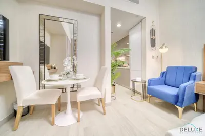 a dining room with a blue chair and a table at Comfortable Studio Apartment at Azizi Riviera 30, Al Merkadh by Deluxe Holiday Homes in Dubai