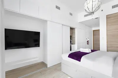 a white bedroom with a bed and a flat screen tv at Summer offer! All Inclusive! Prime Location in Dubai
