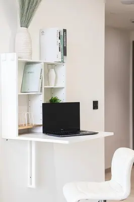 a laptop sitting on a white desk with a chair at Spacious Balcony, King Bed, Pool at JVC Dubai in Dubai