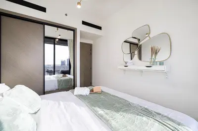 a white bedroom with a large bed and a mirror at Spacious Balcony, King Bed, Pool at JVC Dubai in Dubai