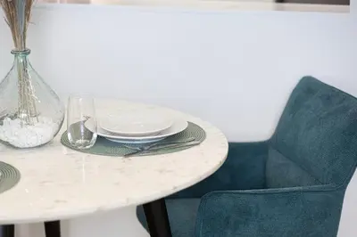 a white table with plates and a vase and a chair at Spacious Balcony, 1BR, Pool, Full Kitchen at JVC in Dubai