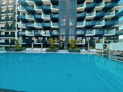 a large swimming pool in front of a building at Spacious Balcony, 1BR, Pool, Full Kitchen at JVC in Dubai