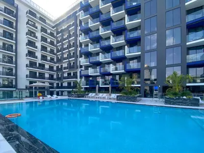 a large swimming pool in front of a building at Spacious Balcony, 1BR, Pool, Full Kitchen at JVC in Dubai