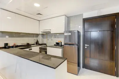 a kitchen with a stainless steel refrigerator and white cabinets at Mira Holiday Homes -Newly 2 bedroom close to metro. in Dubai