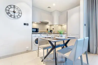 a kitchen and dining room with a table and chairs and a clock at STAY BY LATINEM Luxury 1BR Holiday Home CVR A2504 near Burj Khalifa in Dubai