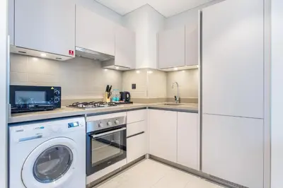 a kitchen with white cabinets and a washer and dryer at STAY BY LATINEM Luxury 1BR Holiday Home CVR A2504 near Burj Khalifa in Dubai