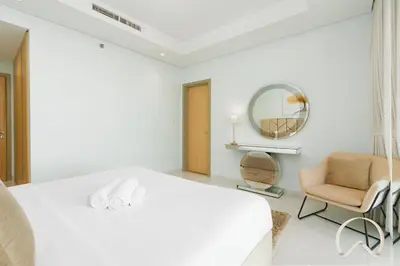 a bedroom with a bed and a chair and a mirror at Oraya - Paramount Midtown Luxurious 2BR with Sea View in Dubai