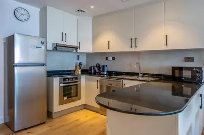 a kitchen with white cabinets and a stainless steel refrigerator at Deluxe - Sea view - Dubai Marina in Dubai