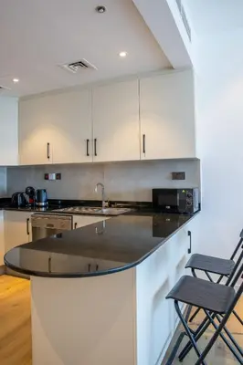 a kitchen with white cabinets and a black counter top at Deluxe - Sea view - Dubai Marina in Dubai