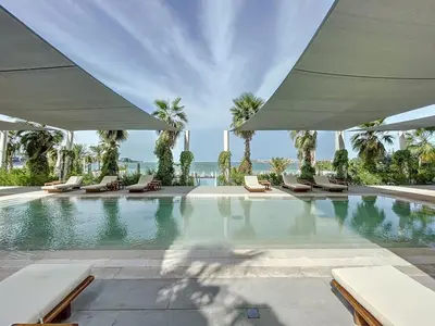 a swimming pool with lounge chairs and the ocean at La Vie, JBR - Cosy Two Bedroom in Dubai