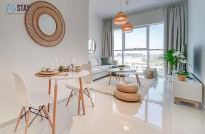 a white living room with a white table and chairs at Lovely One Bedroom Apartment in Dubai