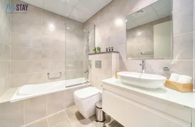 a bathroom with a sink and a toilet and a mirror at Lovely One Bedroom Apartment in Dubai