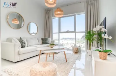 a white living room with a couch and a table at Lovely One Bedroom Apartment in Dubai