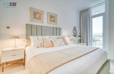 a white bedroom with a large bed and a window at Lovely One Bedroom Apartment in Dubai