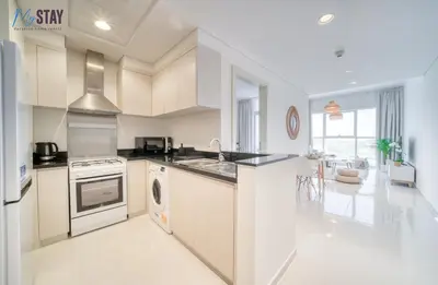 a kitchen with white cabinets and a stove top oven at Lovely One Bedroom Apartment in Dubai
