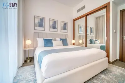 a bedroom with a large white bed and a mirror at Luxurious Two-Bedroom Apartment in Dubai