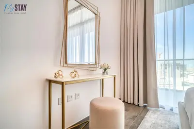 a living room with a mirror and a stool at Luxurious Two-Bedroom Apartment in Dubai