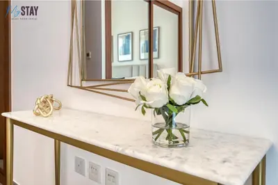 a vase of flowers on a counter with a mirror at Luxurious Two-Bedroom Apartment in Dubai