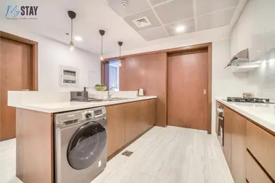 a kitchen with a washing machine in the middle at Luxurious Two-Bedroom Apartment in Dubai