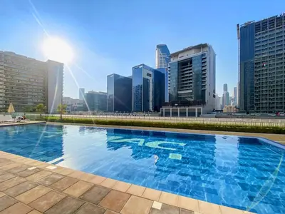 a swimming pool with a city skyline in the background at The Dreamer 1BR Burj Khalifa View Business Bay in Dubai
