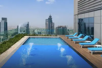 a pool on the roof of a building with lounge chairs at The Cinephile Burj Khalifa View 2BR Dubai in Dubai