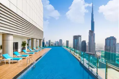 a swimming pool on the roof of a building with a city skyline at The Cinephile Burj Khalifa View 2BR Dubai in Dubai