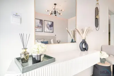 a living room with a mirror and flowers on a counter at Welcoming 1BR Apartment in Ahad Residences Business Bay by Deluxe Holiday Homes in Dubai