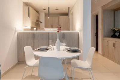 a white dining room with a white table and chairs at SEVEN PALM by Design Studio 1BR in Dubai