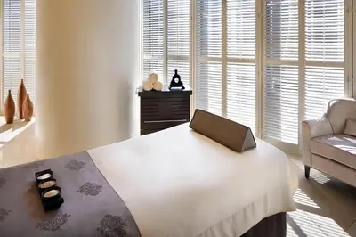 a bedroom with a bed and a chair and windows at Suitestay-Formerly Address Dubai Mall Residence-Downtown in Dubai