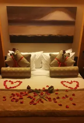 a bed with two pillows and red flowers on it at Suitestay-Formerly Address Dubai Mall Residence-Downtown in Dubai