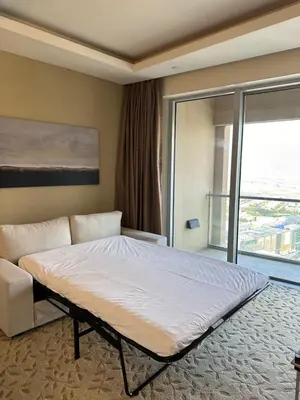 a bedroom with a bed and a couch and a window at Emaar Residence Fashion Avenue - formerly Address Dubai Mall in Dubai
