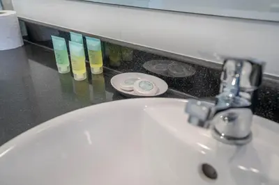 a bathroom sink with aaucet and some toothbrushes at Budget Friendly Production City in Dubai