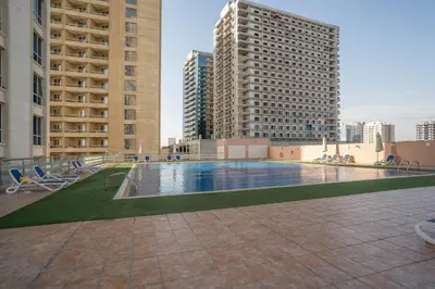 a swimming pool in a city with tall buildings at Budget Friendly Production City in Dubai