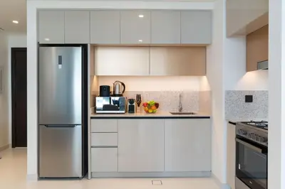a kitchen with white cabinets and a stainless steel refrigerator at Elegant 1BHK Beach Front Perfect Getaway in Dubai