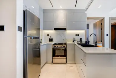 a kitchen with white cabinets and a stove top oven at Serene City Stays Binghatti Canal Luxe 2BR in Dubai