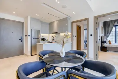 a dining room with a table and blue chairs at Serene City Stays Binghatti Canal Luxe 2BR in Dubai