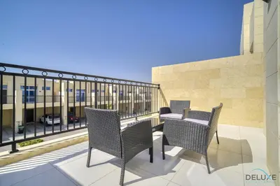a patio with chairs and a table on a balcony at Exquisite 4BR Townhouse at DAMAC Hills 2, Dubailand by Deluxe Holiday Homes in Dubai