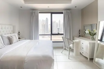 a white bedroom with a large bed and a window at Frank Porter - Al Waleed Paradise in Dubai