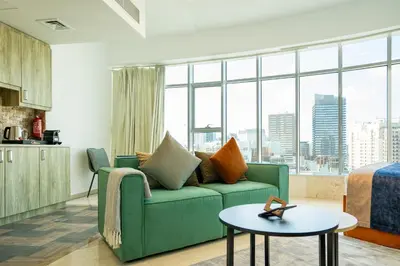 a living room with a green couch and a large window at CitiHome - Prime Stylish Studio in Sports City in Dubai