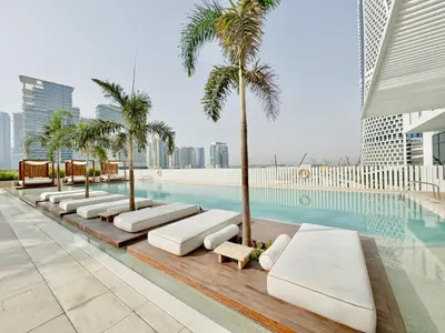 a row of chaise lounge chairs next to a swimming pool at Studio with Burj Khalifa View - Upside Living in Dubai