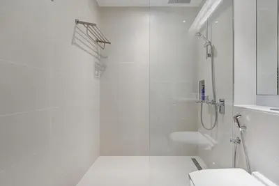 a white bathroom with a shower and a toilet at Trophy - Serene Abode near the Coast in Dubai