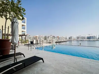 a large swimming pool with chairs and an umbrella at Trophy - Serene Abode near the Coast in Dubai