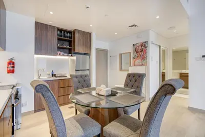 a kitchen and dining room with a glass table and chairs at Trophy - Serene Abode near the Coast in Dubai
