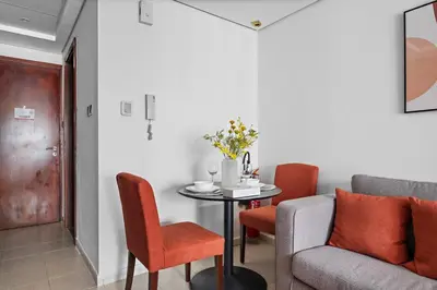 a living room with a table and chairs and a couch at StoneTree - Cozy Studio - JLT in Dubai