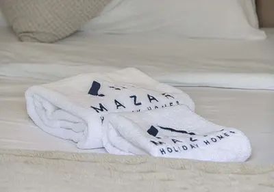 two towels sitting on top of a bed at 1BR Gem with Pool 15 Mins to Downtown Dubai in Dubai