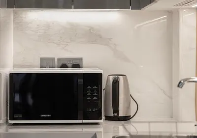 a microwave sitting on a counter next to a coffee maker at 1BR Gem with Pool 15 Mins to Downtown Dubai in Dubai